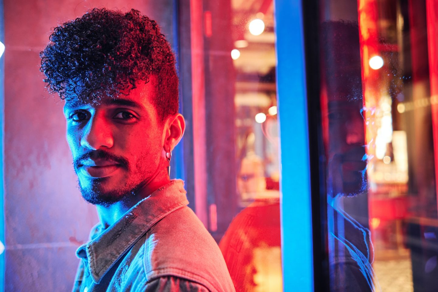 young-hispanic-man-close-to-a-neon-light-with-blue-and-red-lights-e1698314047406.jpg